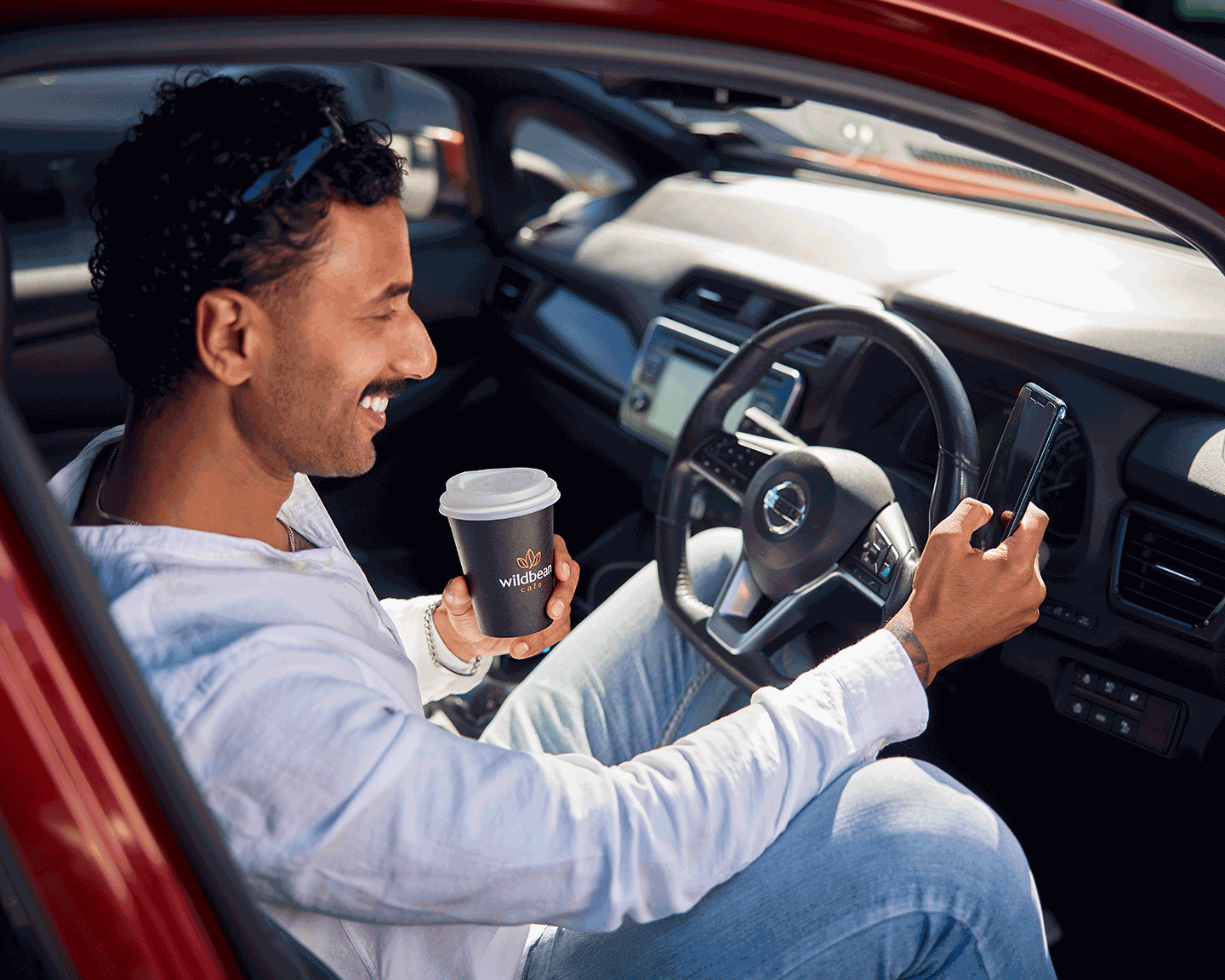 A man smiles drinking his Wild Bean coffee whilst he looks through the bp pulse aop.