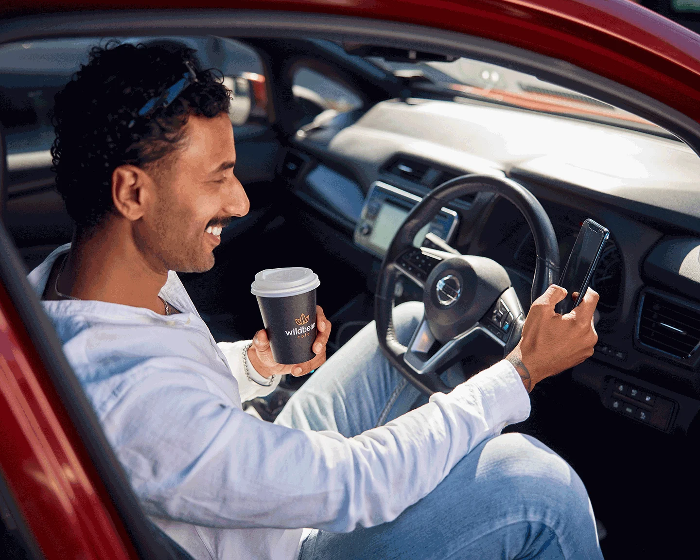 A man smiles drinking his Wild Bean coffee whilst he looks through the bp pulse aop.