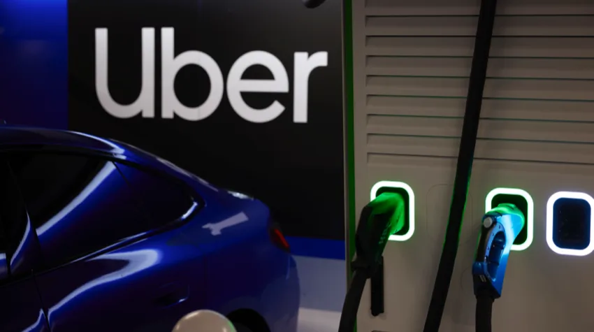 The uber logo sits behind an electric vehicle which is charging on a bp pulse EV charger.