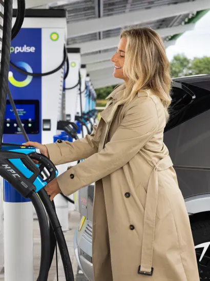 A woman charging her electric vehicle at a bp pulse charging station.