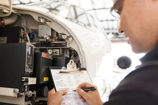 Aircraft technician reviewing maintenance documentation next to aircraft.