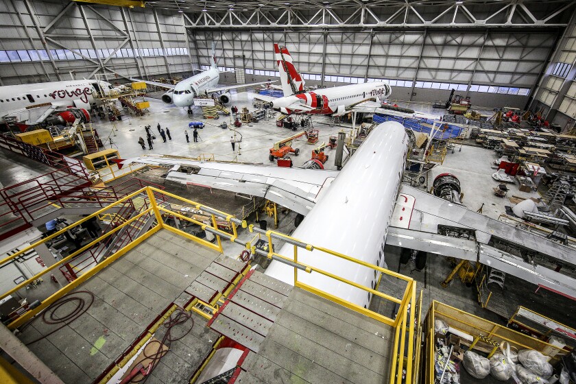 Multiple aircraft positioned inside a maintenance facility preparing for service.
