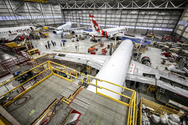 Multiple aircraft positioned inside a maintenance facility preparing for service.