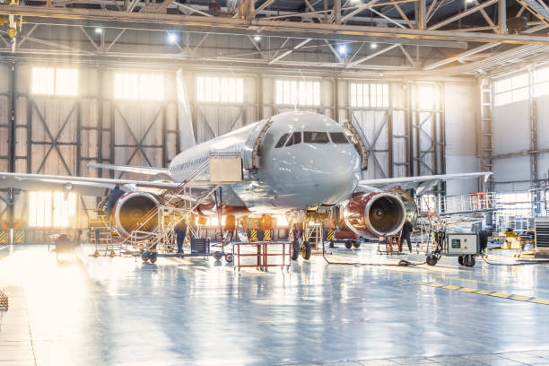 Aircraft technicians performing heavy maintenance inside an aviation hangar.