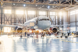 Aircraft technicians performing heavy maintenance inside an aviation hangar.