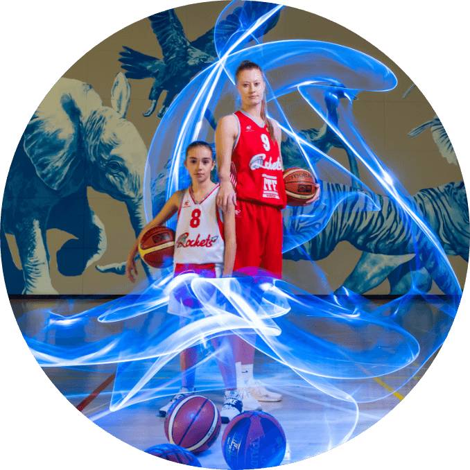 Two young girls standing and holding a basketball