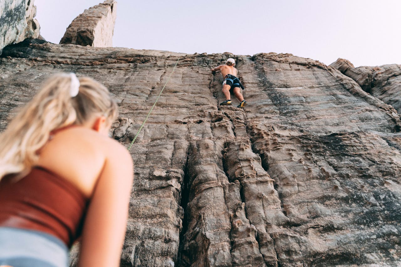 rock climbing | woman and man climbing up a rocky wall