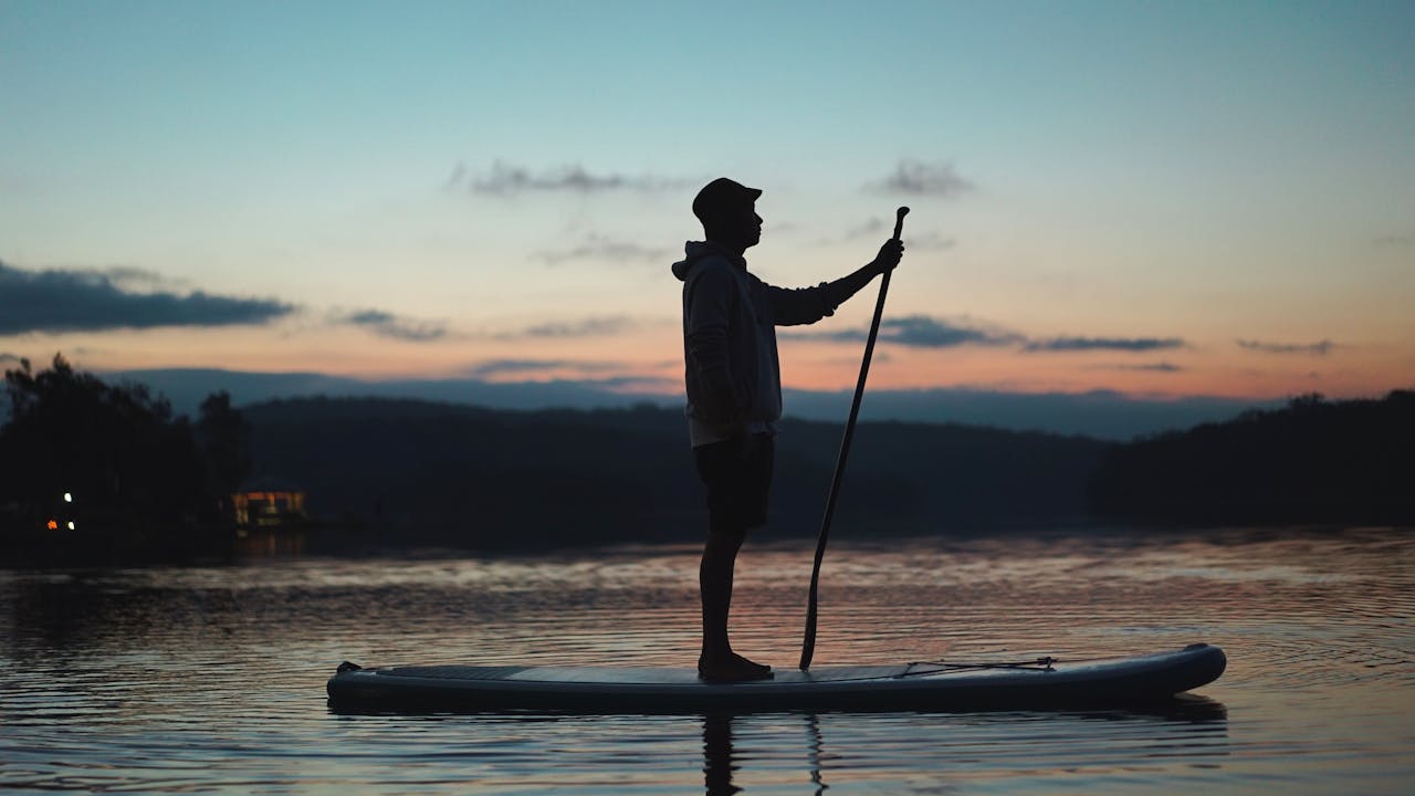 man standing on paddleboard | man standing on paddleboard