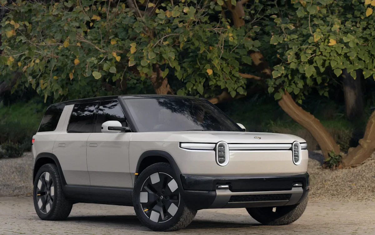 Rivian R2 vehicle parked under a large tree.