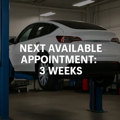 Electric SUV on a lift inside an EV service center, representing long repair wait times.