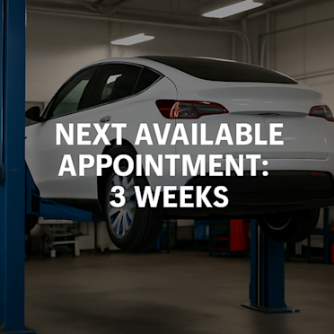 Electric SUV on a lift inside an EV service center, representing long repair wait times.