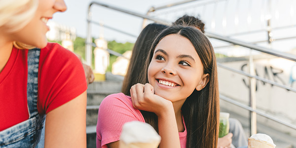 Two young friends enjoying ice cream on outdoor steps, smiling and sharing a joyful moment together