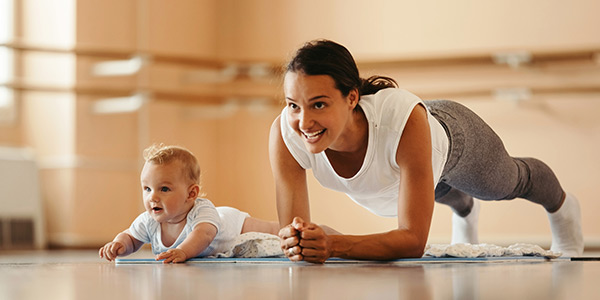 A mother and a newborn child performing exercises on the floor