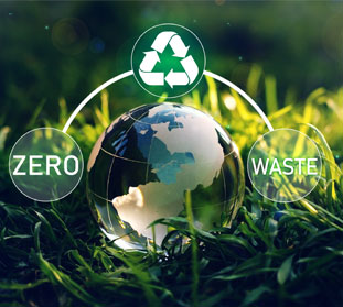 A glass globe with recycling symbols on it sits in a field of green grass. Text on the globe says "Zero Waste"