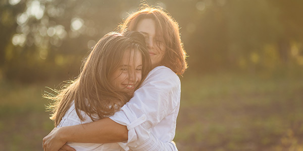 Mother and daughter hugging each other in nature