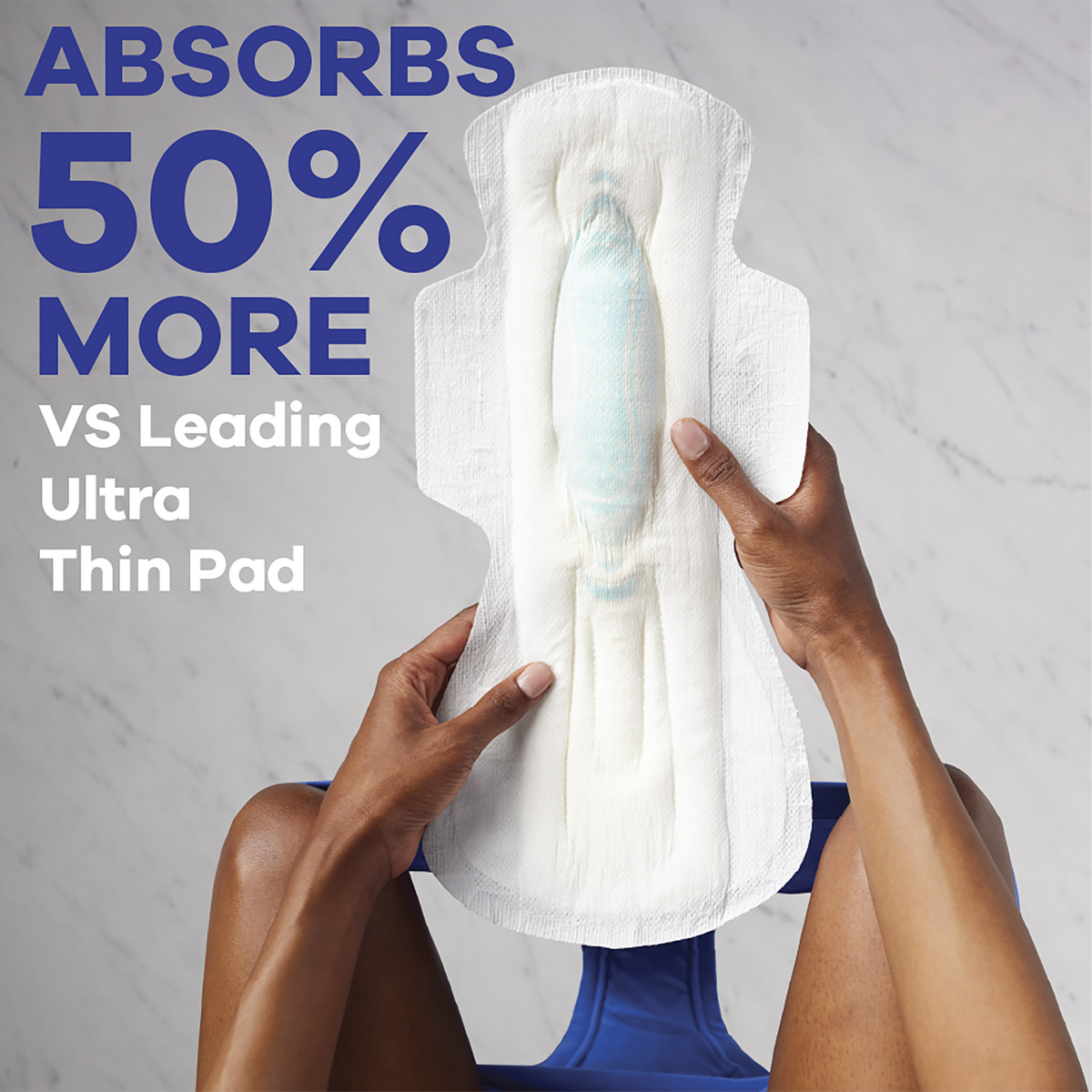 Hands holding a large menstrual pad that absorbs 50% more than leading ultra-thin pads, displayed on a surface