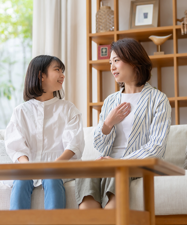 A mother and daughter share a warm, joyful moment, smiling and leaning their foreheads together in an intimate setting