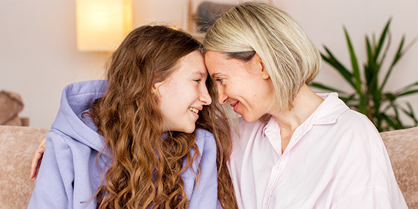 Mother and daughter touching each other with forehead and smiling. 