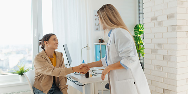 The girl sitting in the doctor's office and shaking hands with the doctor in a white uniform