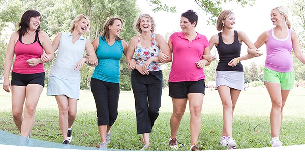 A diverse group of women walking together in a park, smiling and enjoying their time outdoors