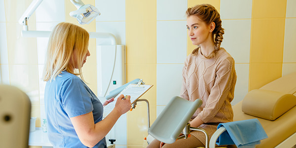 A healthcare professional discusses treatment options with a young woman in a medical office setting