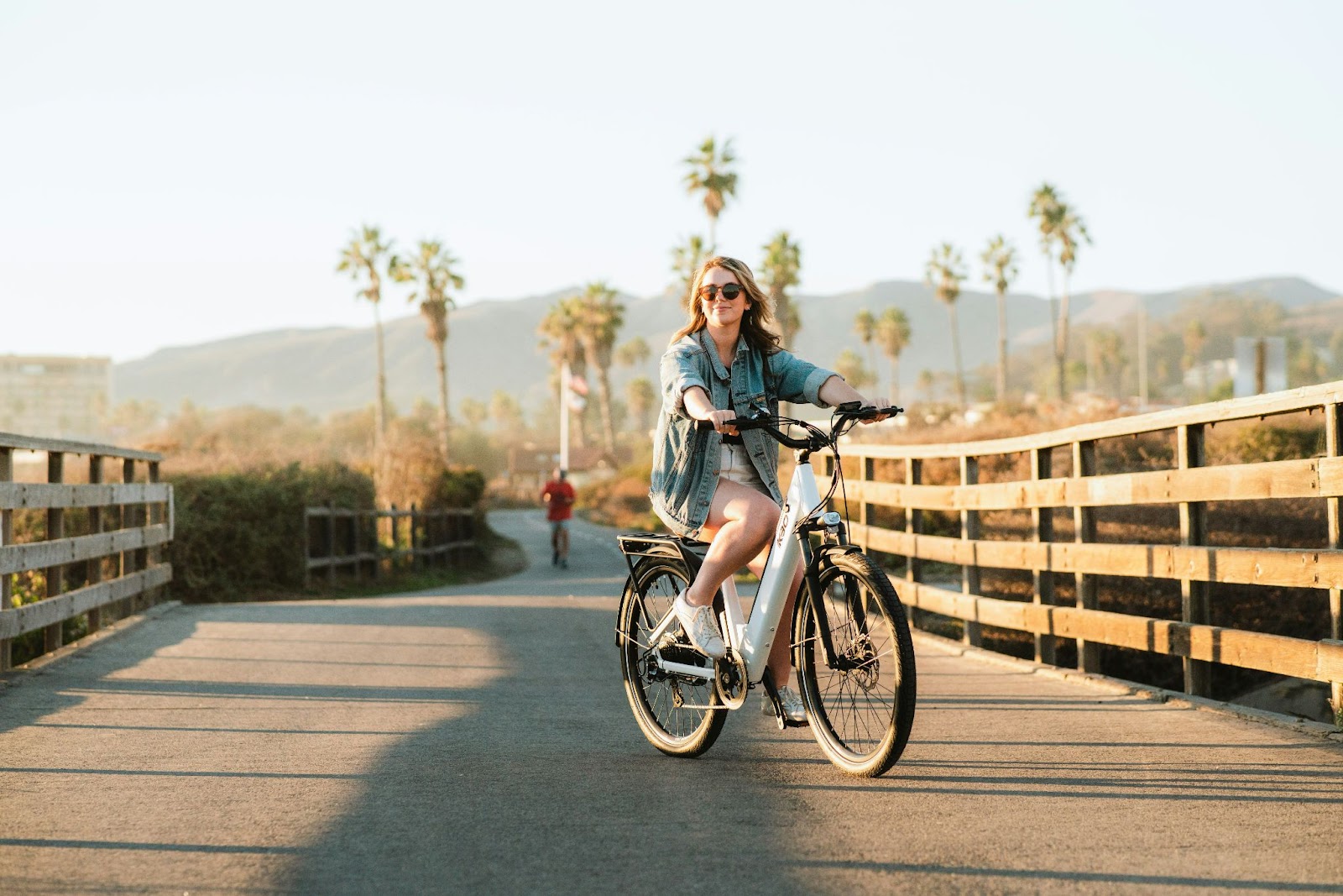 A woman riding a bike across a bridge