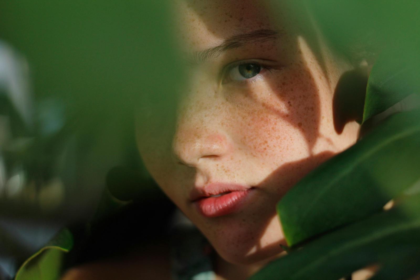Close-up Photo of Woman Hiding Behind Green Leaves