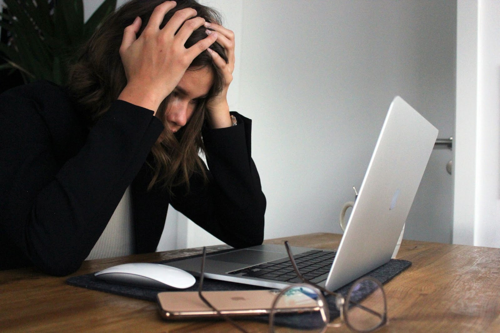 Woman in black long sleeve shirt covering her face with her hands