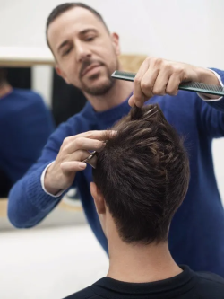 coiffeur qui peigne les cheveux d'un homme