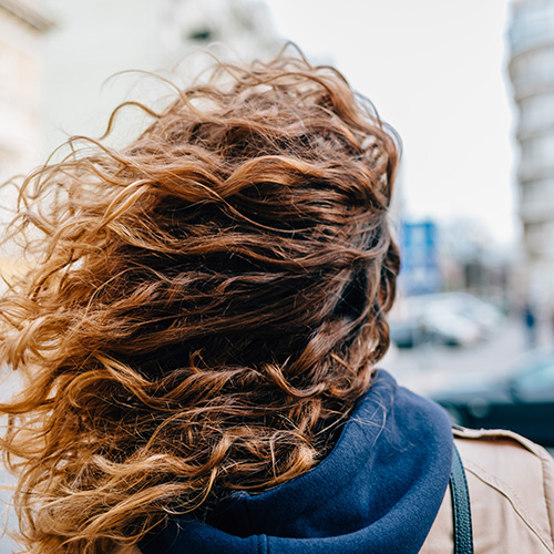 Gros plan de longs cheveux bruns bouclés et ondulés, montrant une texture riche et du volume.