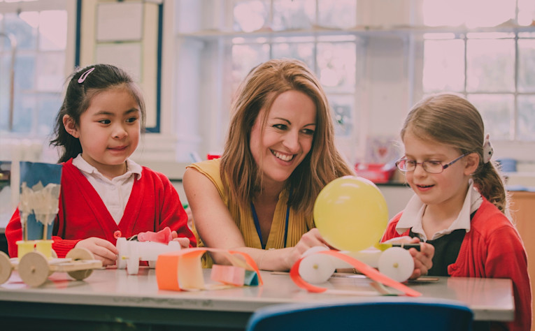 A female primary school teacher with two children in red cardigans