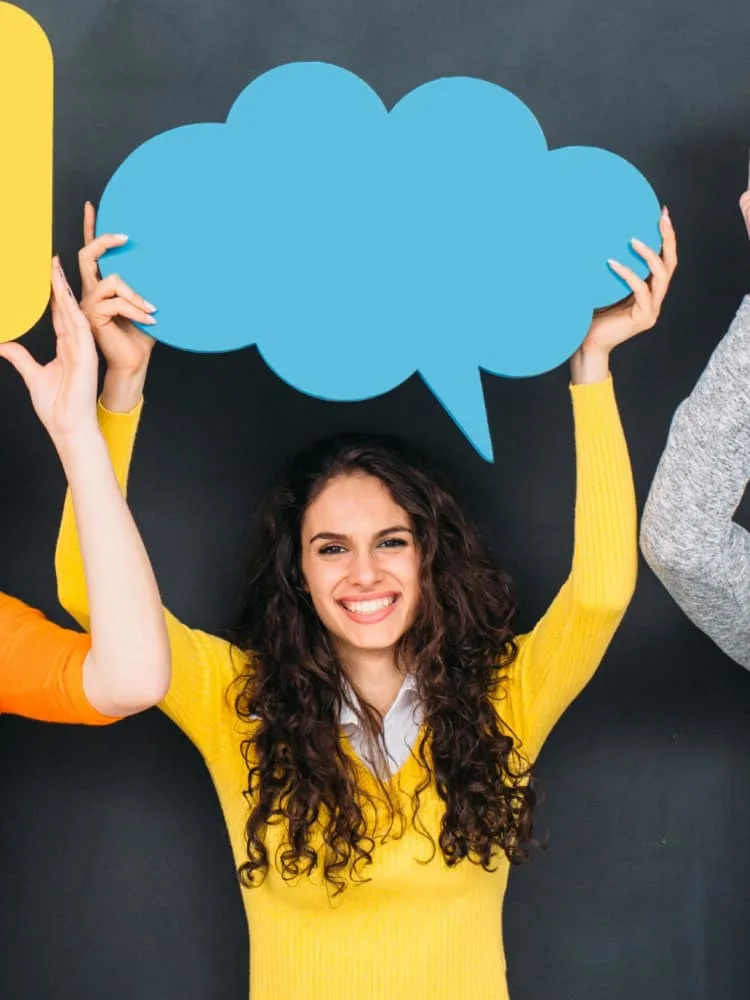 group of people holding colorful speech bubbles