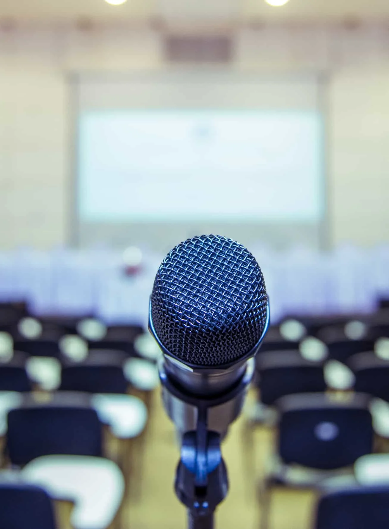 Microphone over abstract blurred photo of conference hall