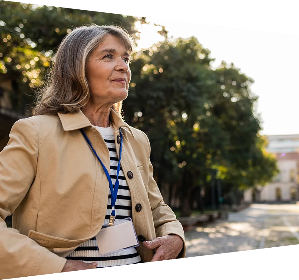 Middle-aged woman standing in the road of a university campus looking optimistically toward the distance.