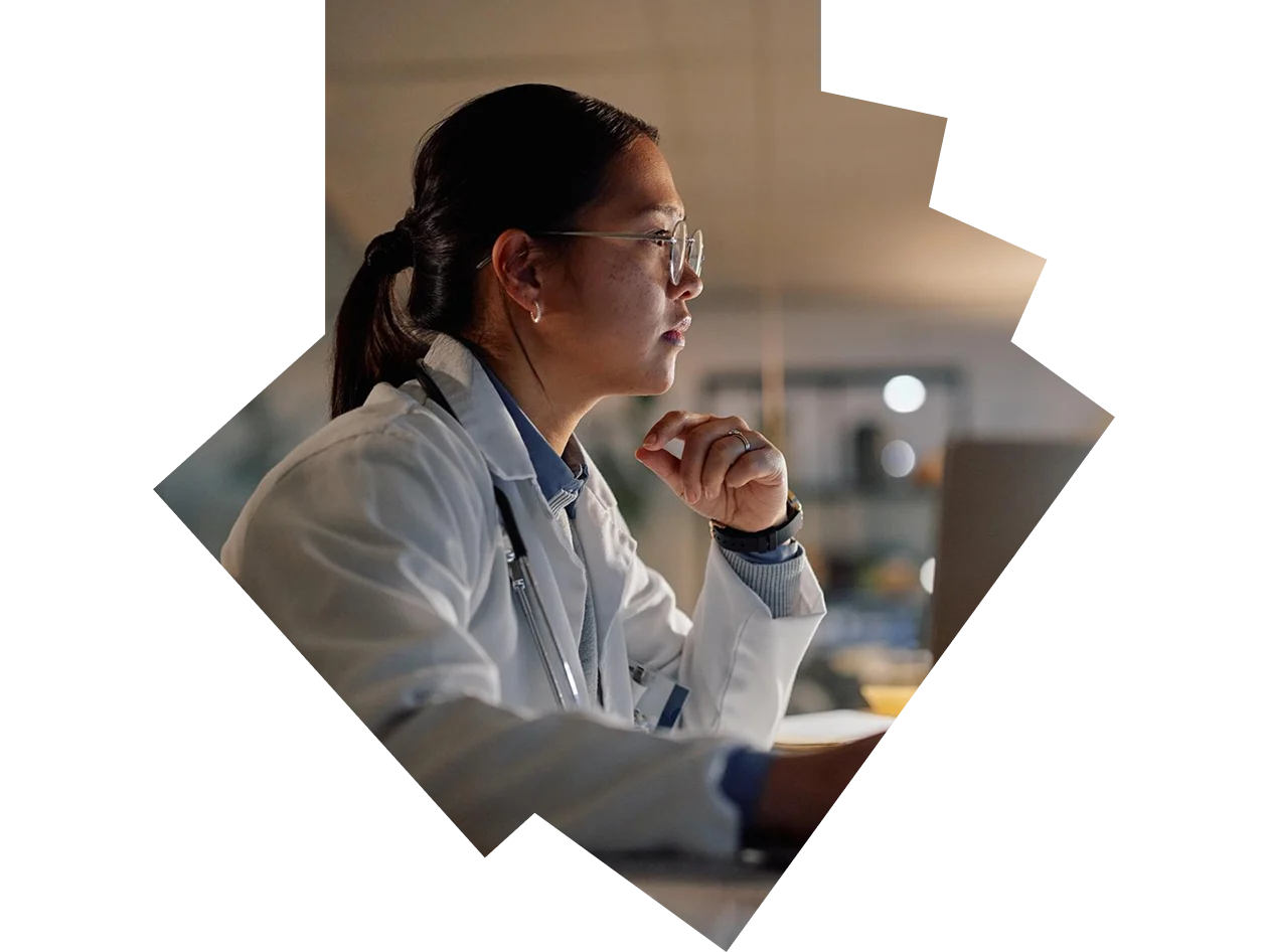 Senior female doctor looking thoughtfully at laptop in her office