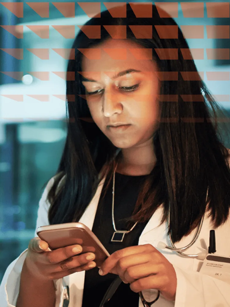 Young doctor standing next to window looking at her phone