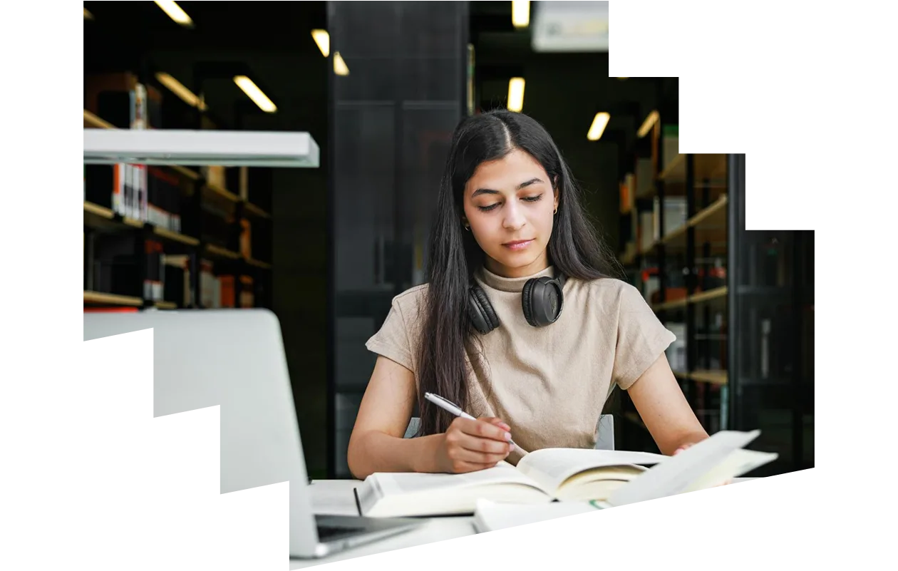 Female Student Studying With Books and Laptop in Library