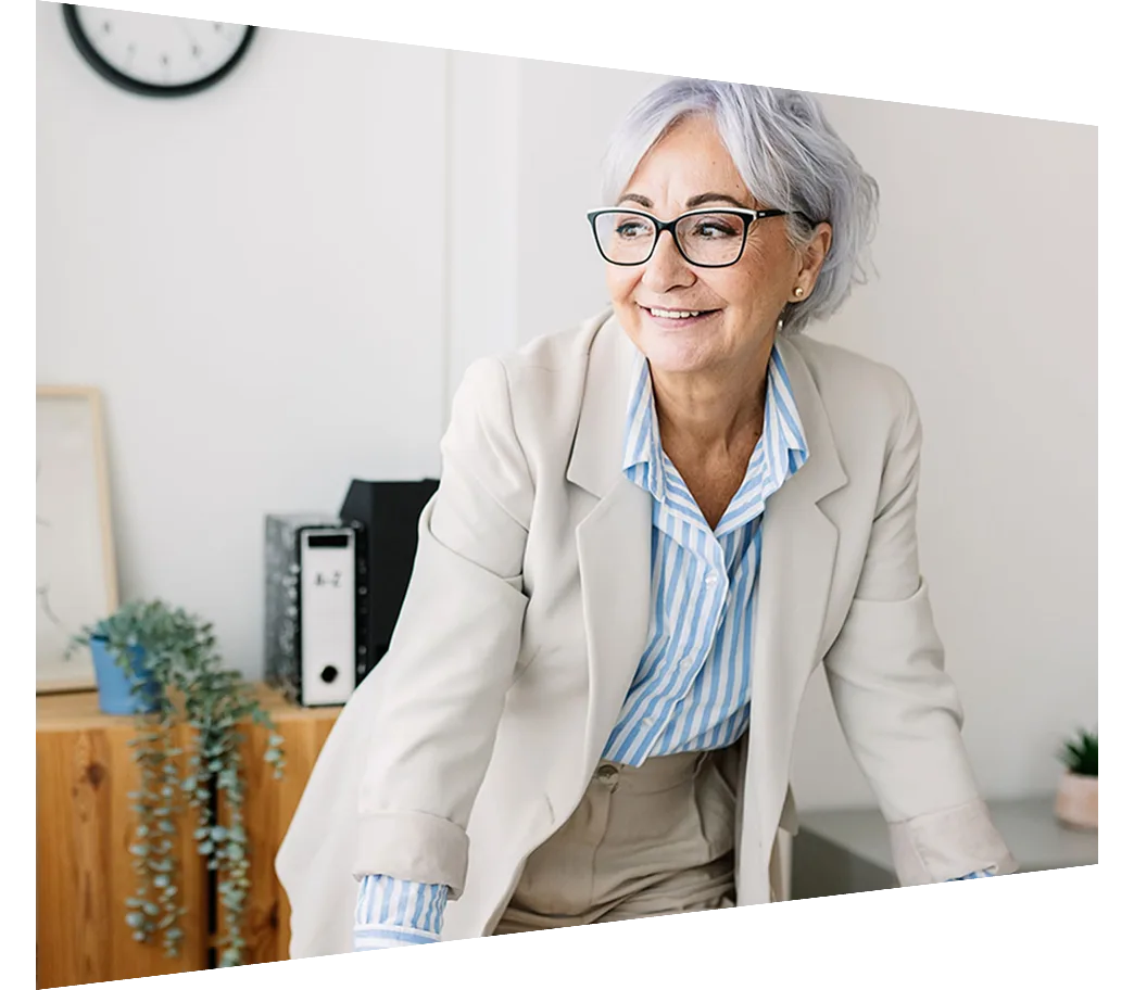 Mature woman leaning against desk in her office