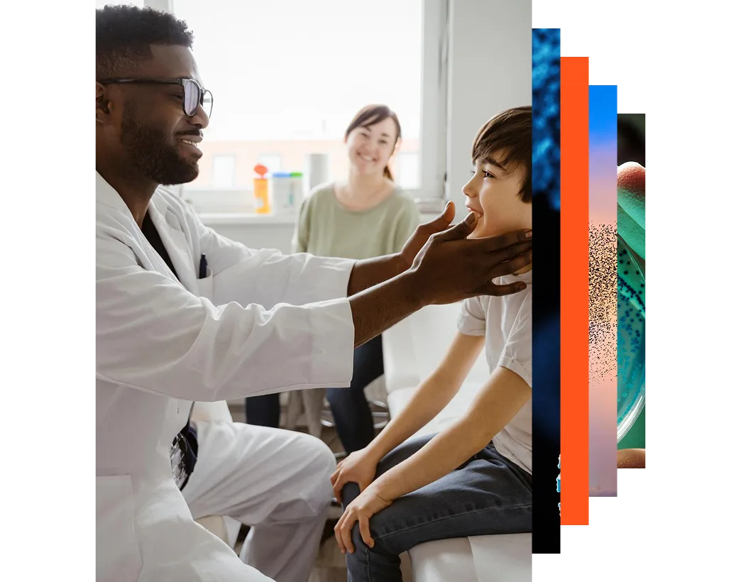 Smiling male pediatrician examining neck of boy sitting on bed at healthcare center