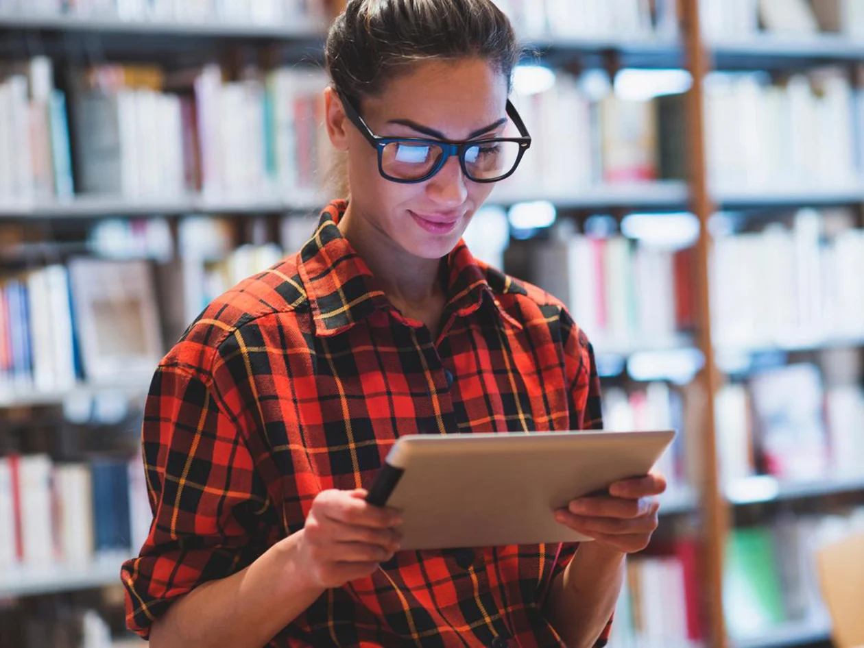 Young woman using tablet in library