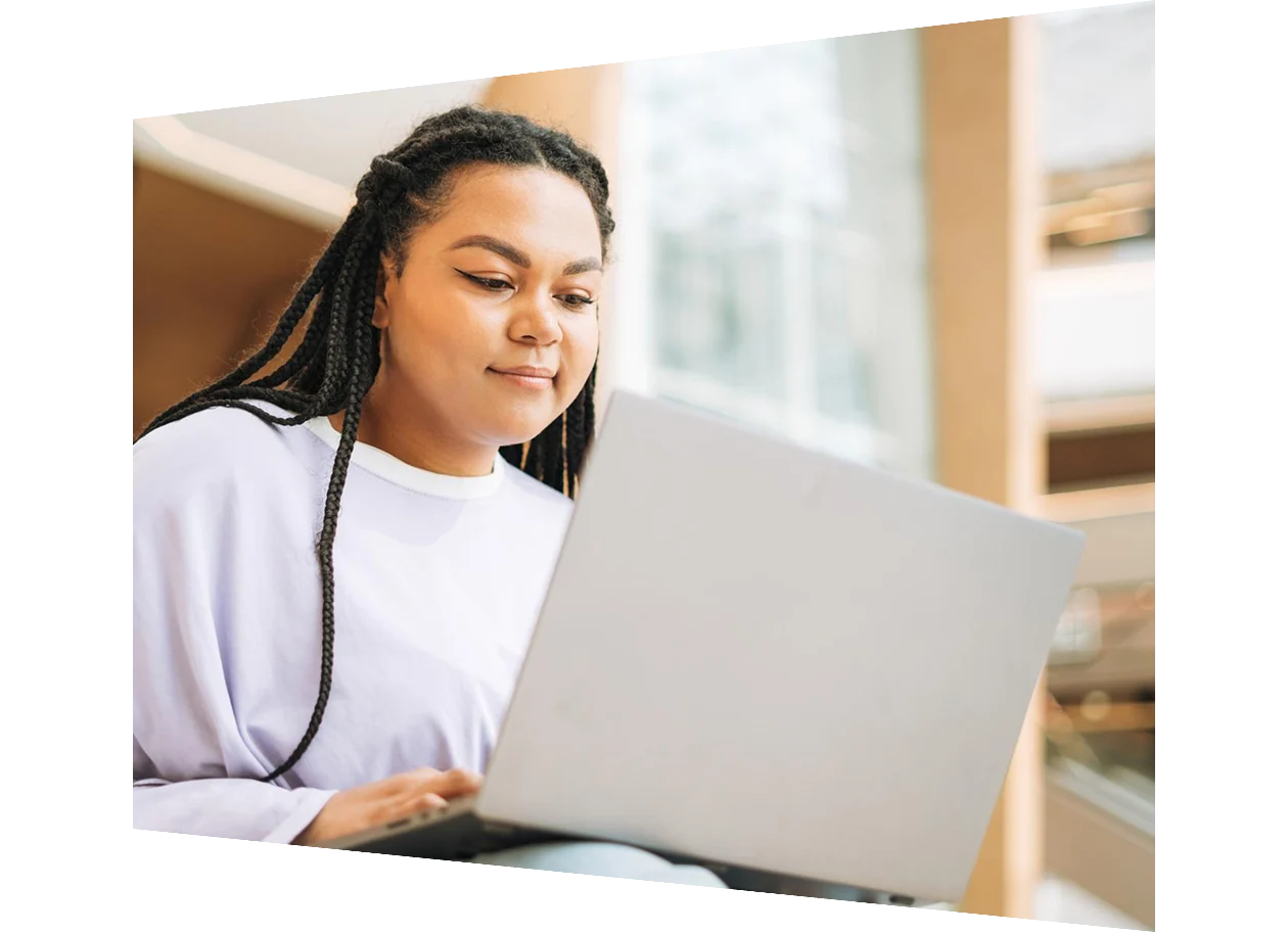 Mix race girl student working on a laptop on stairs in a modern building