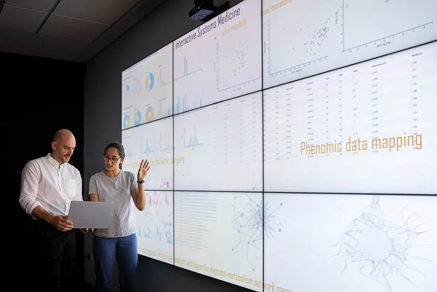 Researchers in front of large wall of screens