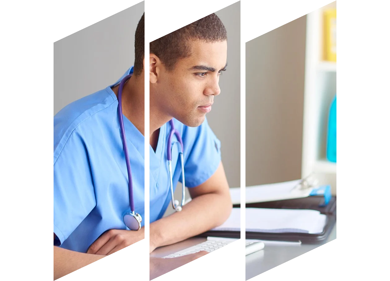 Medical student wearing scrubs at his desk looking at his computer screen