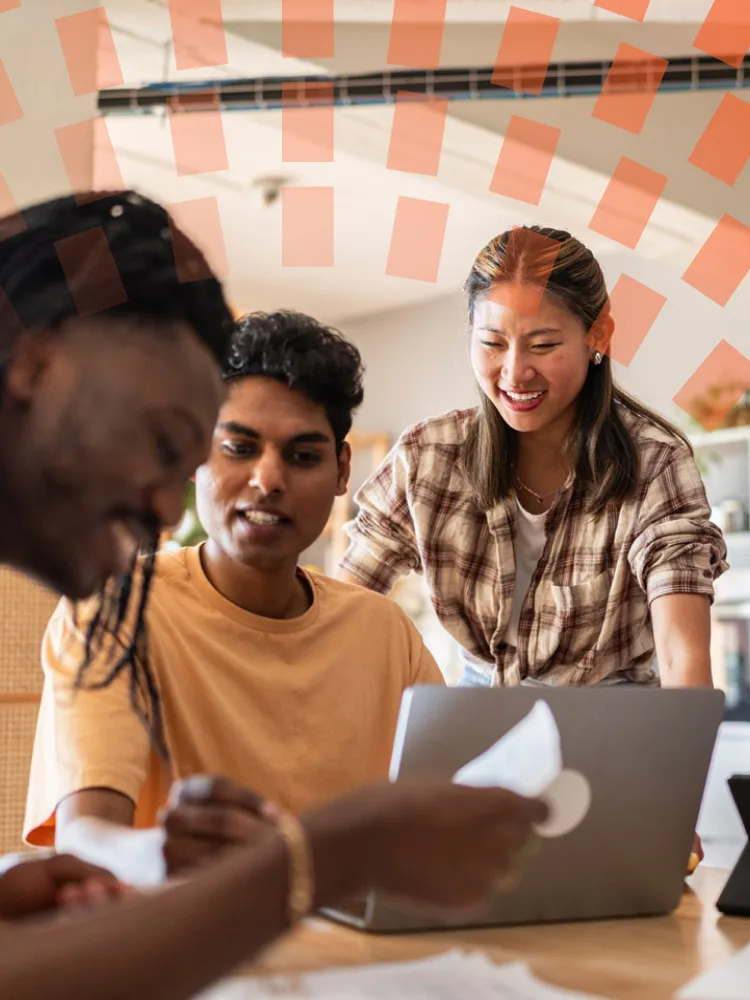 Three colleagues collaborating on laptop in colorful lounge area