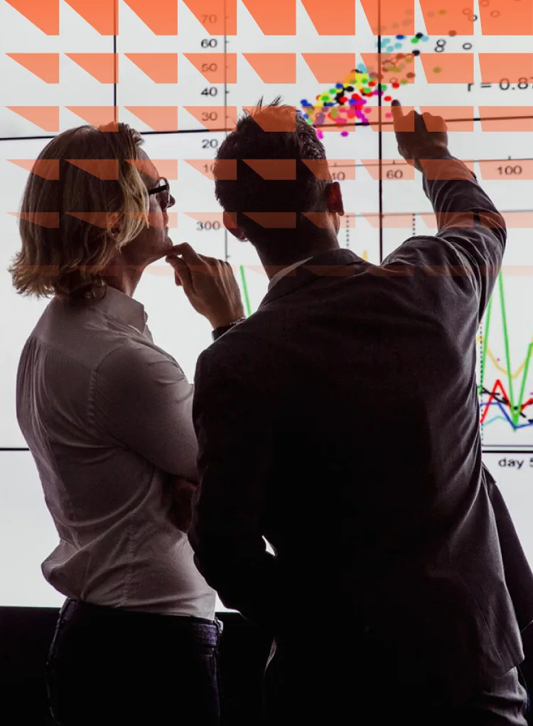Business men in a dark room standing in front of a large data display