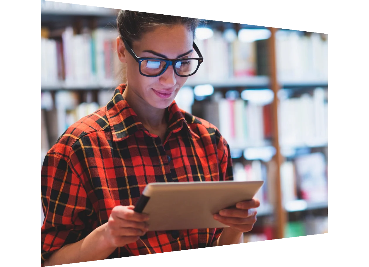 Young woman looking at digital tablet in library