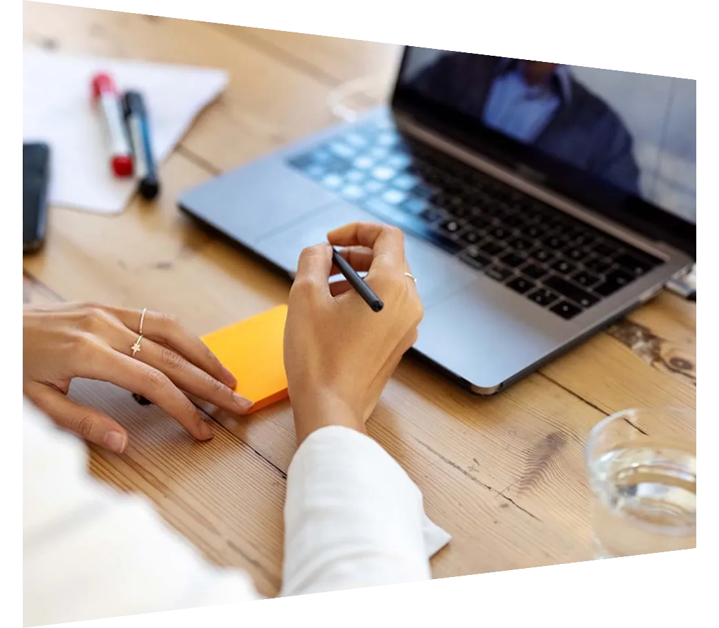 Woman taking notes in front of laptop