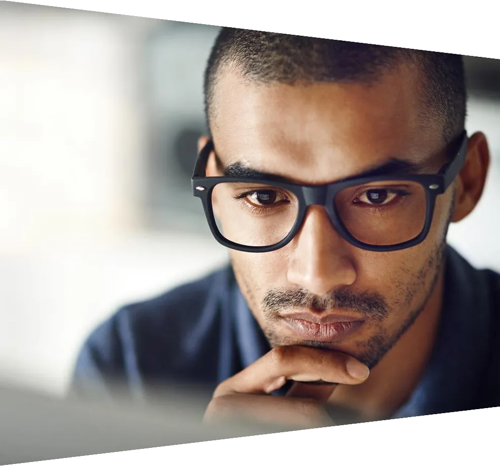 A thoughtful-looking man wearing glasses looking at a monitor