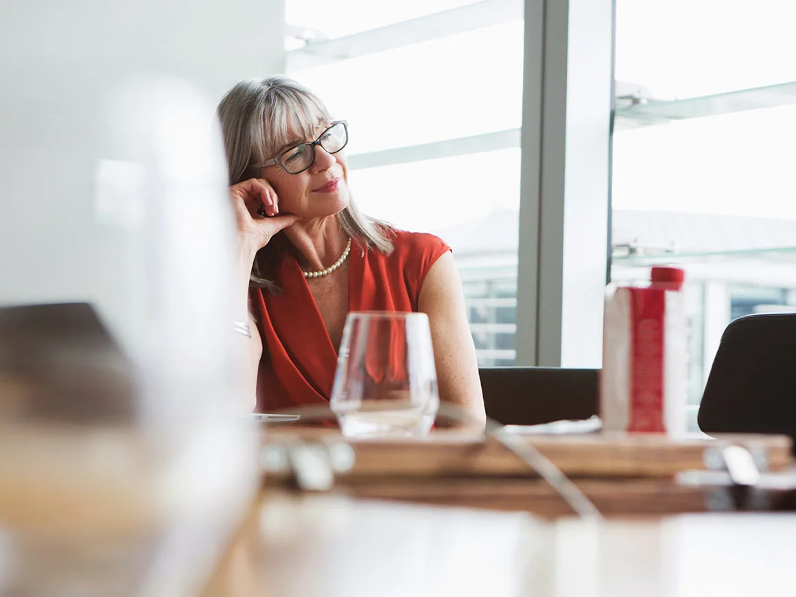 Professional woman looking out window sitting at conference table