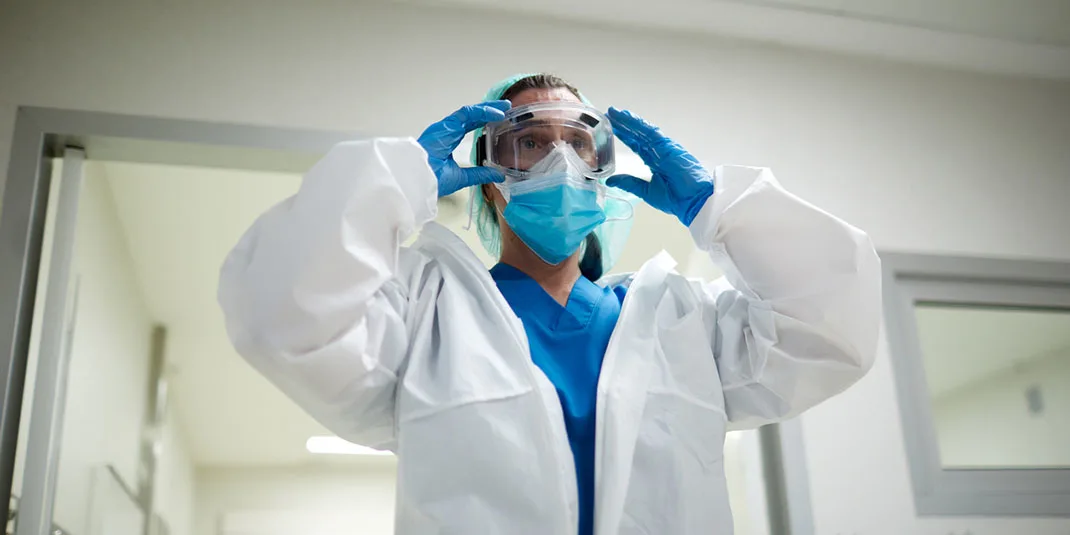 Female doctor getting dressed with PPE protective clothes (© istock.com/Tempura)